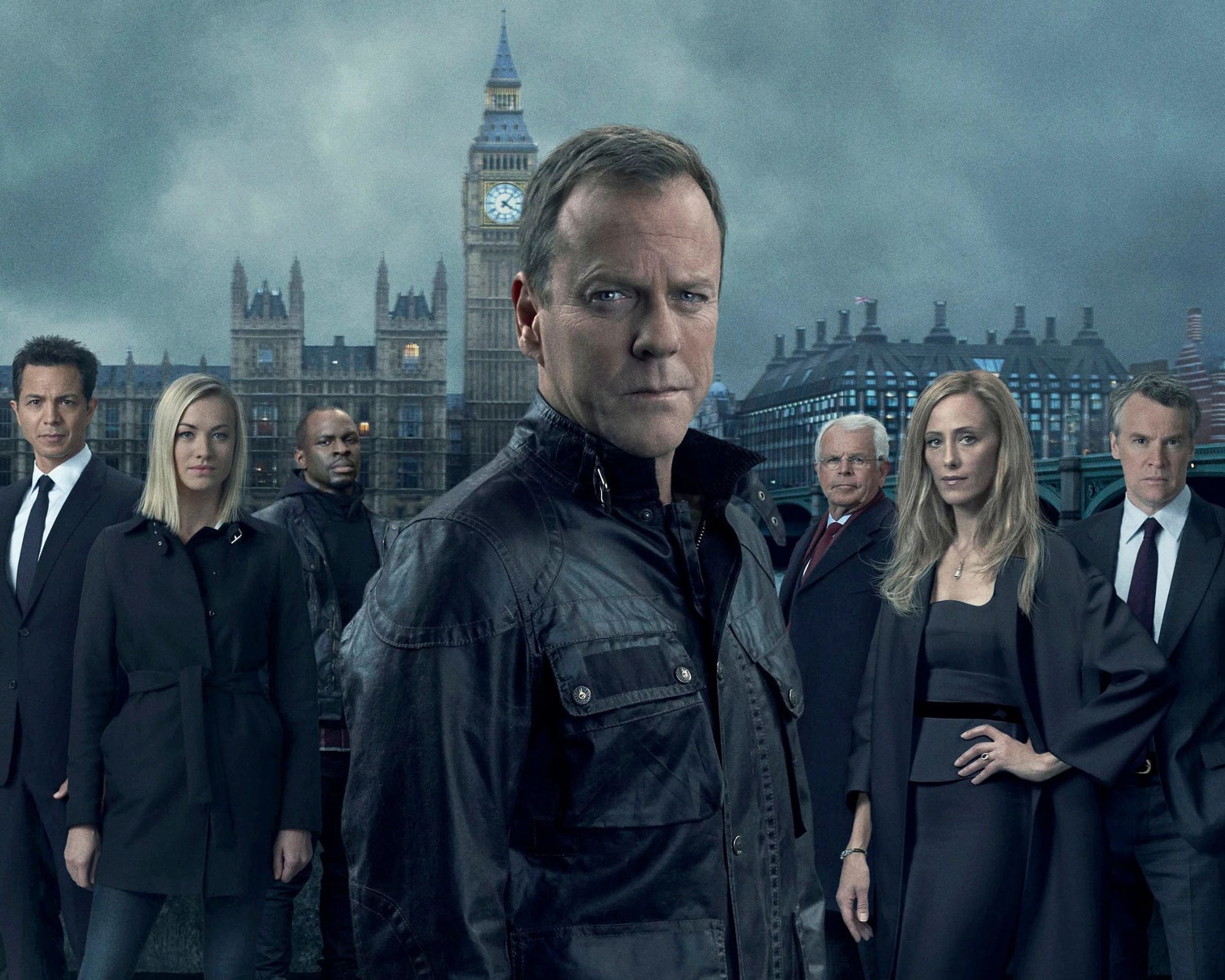 A group of actors standing in front of a dramatic London backdrop featuring Big Ben and the Houses of Parliament under a stormy sky. The central figure wears a dark leather jacket and faces forward, while the others wear dark formal clothing.